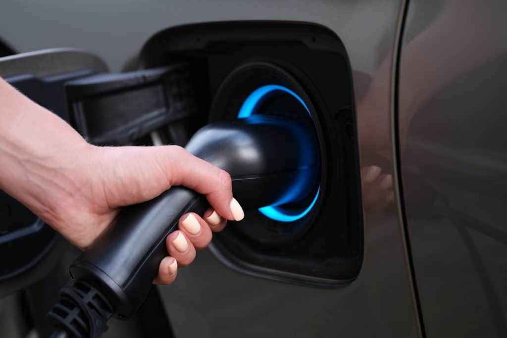 Woman charging car using electric plug closeup. Environmentally friendly fuel concept